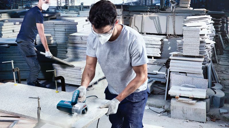 قاطع البلاط الماسي Bosch GDC 140 قيد الاستخدام على بلاطة حجرية.