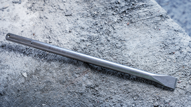 رأس إزميل موضوع على سطح خرساني خشن.