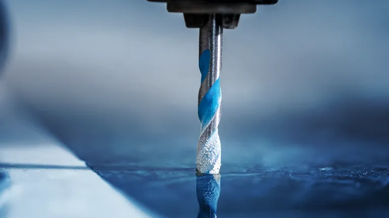 Drill bit making a hole in a reflective tile surface.