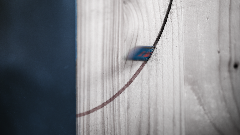 Jigsaw blade cutting a curved line through a piece of wood.