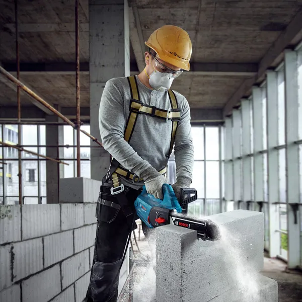 A person wearing safety equipment cuts an AAC block with a power cutter.