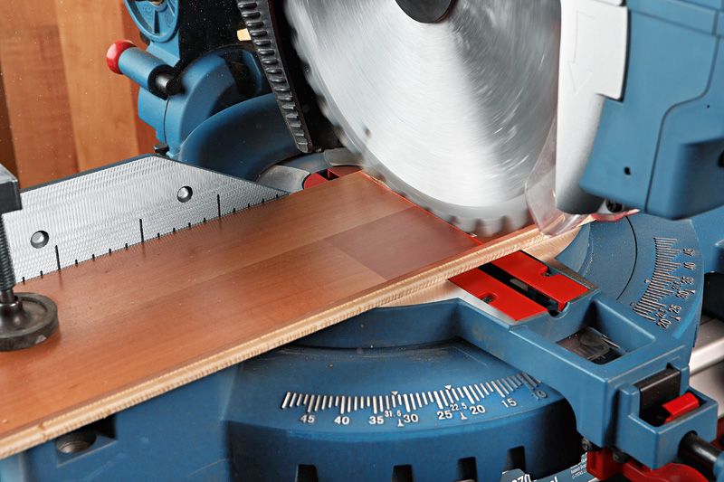 Sliding miter saw making an angled cut through a wooden board.