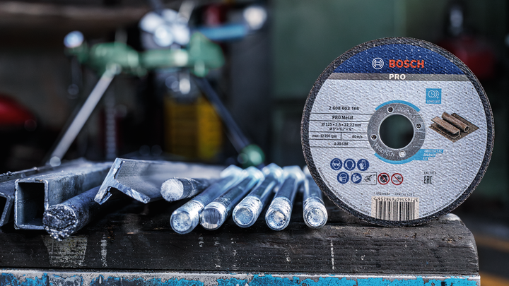 Cutting disc for metal placed beside steel rods on a workshop table.