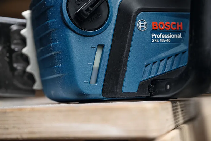 Close-up of a cordless chainsaw resting on a wooden surface.