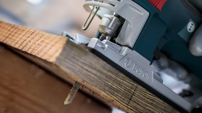 Jigsaw cutting through a thick wooden plank.