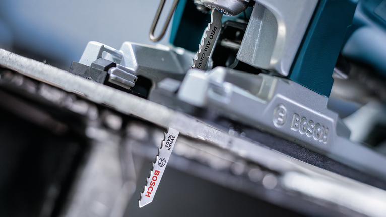 Close-up of a jigsaw blade cutting through a metal sheet.