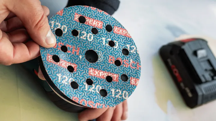 Person attaches sanding disc to a power sander.