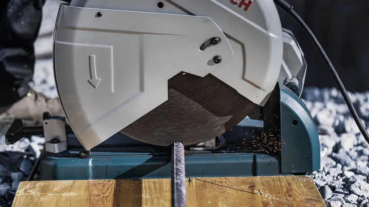 Metal cutting saw slicing through a steel rod with sparks flying.