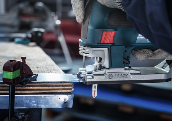 Person wearing safety equipment cuts sheet metal with a jigsaw.