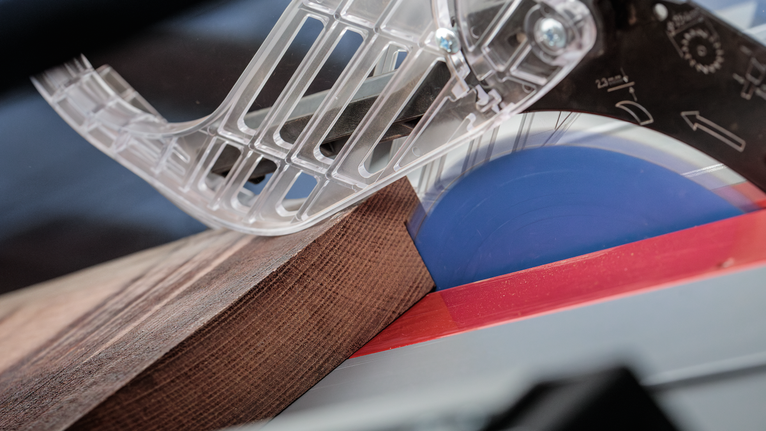 Circular saw cutting through a piece of wood under a transparent blade guard.
