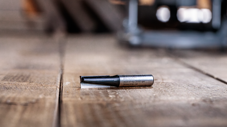 Router bit resting on a wooden surface in a workshop.