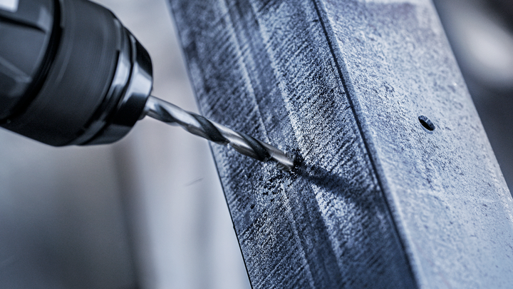 Drill making a hole in a steel beam.