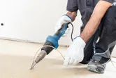 A person wearing safety equipment uses a heat gun to weld flooring.