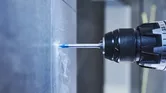 Power drill creating a hole in a tile wall.