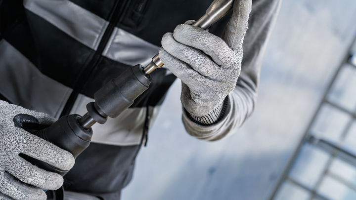 Person wearing safety equipment attaches a drill bit to a power tool.