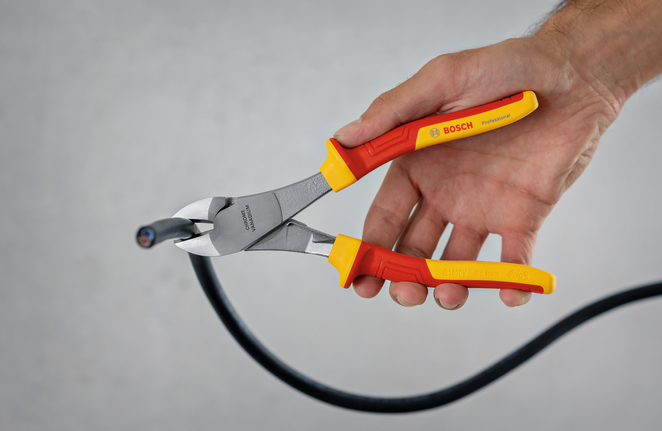 Person cutting a black cable with insulated side cutters.