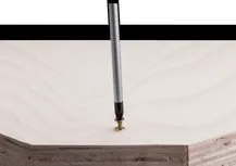 Screwdriver bit driving a screw into a piece of light-colored wood.