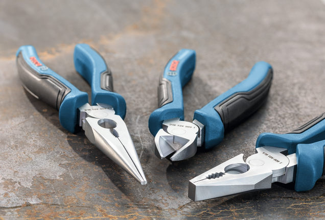 Three blue-handled pliers arranged on a metal surface.