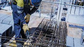 Person wearing safety equipment secures rebar at a construction site.