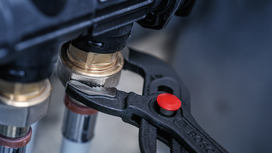 Adjustable pliers tightening a brass pipe fitting.