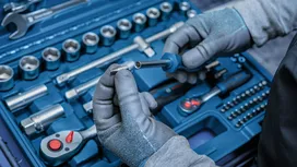 Person wearing safety equipment selects a socket from a tool kit.