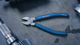 Blue-handled cutting pliers resting on a workshop table.