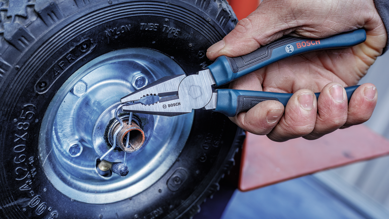 Person uses pliers to adjust a spring on a metal wheel hub.