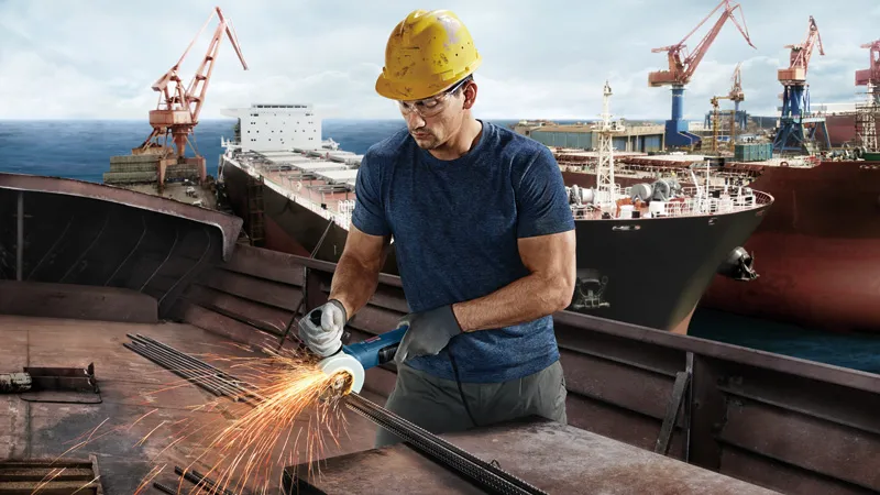 Ouvrier rectifiant le métal, chantier naval.