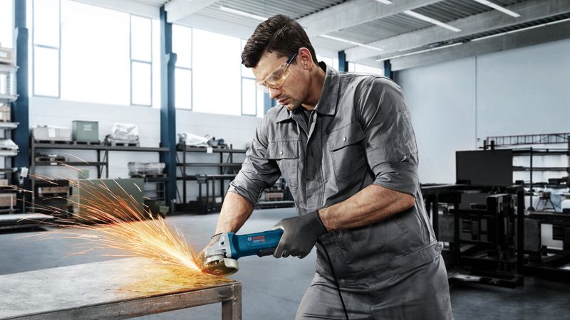 Homme broyant une table en métal.