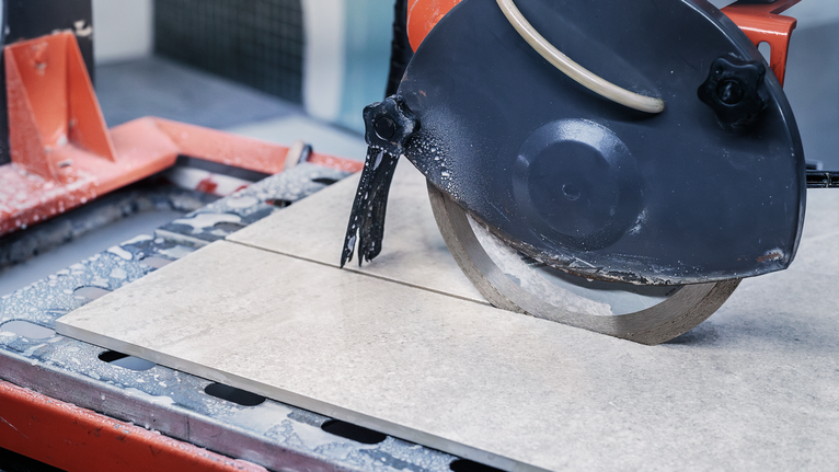 Machine de découpe de carreaux coupant un carreau de céramique dans un atelier.