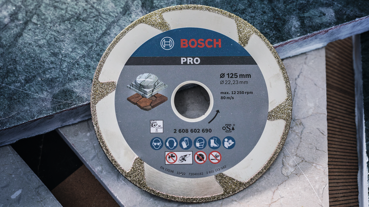 Disque de coupe diamanté placé sur des dalles de carreaux empilées.