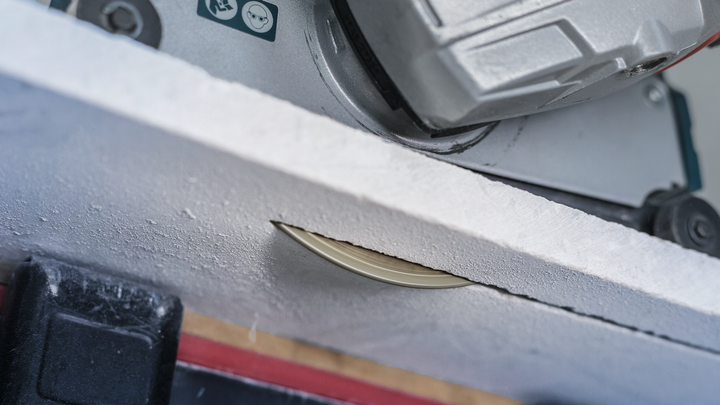 Scie circulaire coupant une planche blanche.