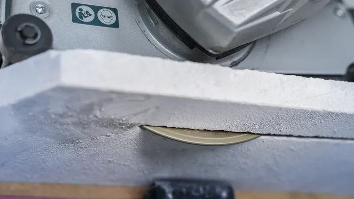 Lame de scie circulaire coupant une plaque de plâtre.