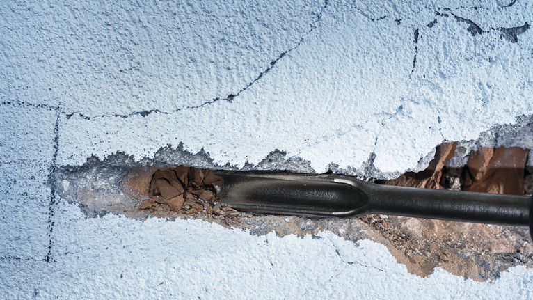 Outil de ciseau cassant le plâtre sur un mur peint.