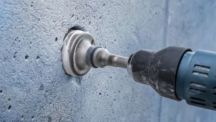 Carotteuse créant un trou circulaire dans un mur en béton.