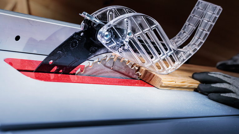 Scie circulaire coupant du bois, personne portant un équipement de sécurité.