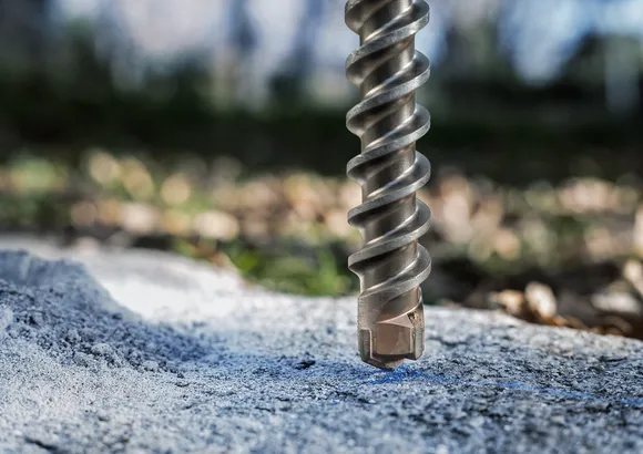 Grand foret à maçonnerie positionné au-dessus d'une surface en béton rugueuse à l'extérieur.
