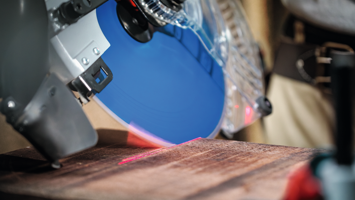 Une scie circulaire équipée d'un guide laser se prépare à découper une planche de bois.