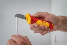 Une personne utilise un couteau isolé pour couper un fil recouvert de plastique.