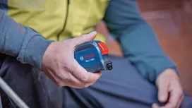 Personne portant un équipement de sécurité tenant un mètre ruban.