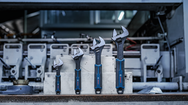 Quatre clés à molette de tailles différentes sont présentées sur des blocs de béton dans un environnement industriel.