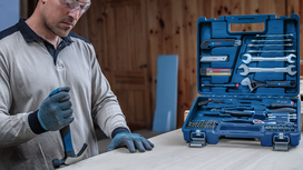Une personne portant un équipement de sécurité utilise un marteau à côté d'une boîte à outils ouverte posée sur une table.