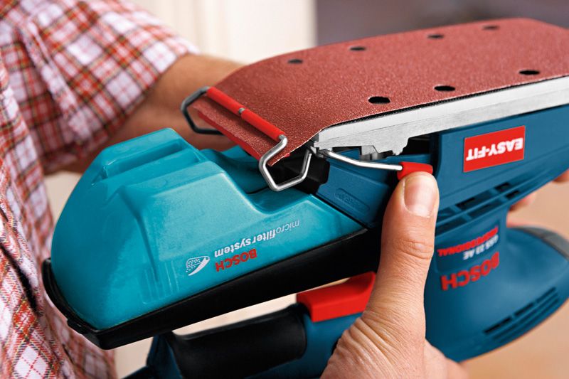 A person attaches sandpaper to an orbital sander.