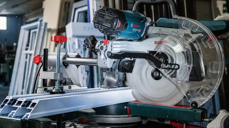 Miter saw cutting an aluminum profile in a workshop.