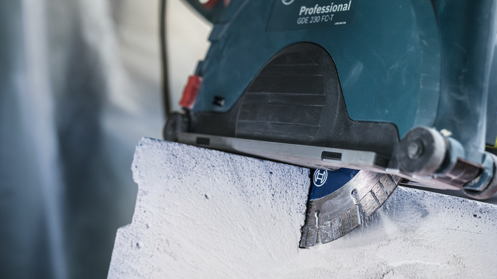 Circular saw cutting through concrete, dust visible near the blade.