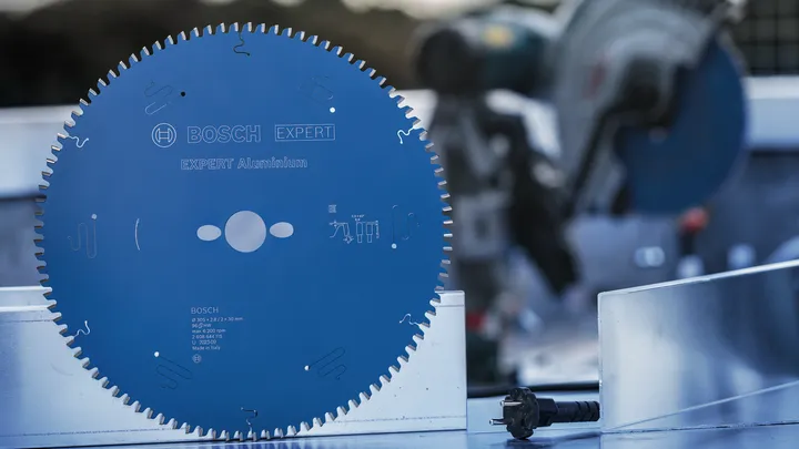 Large blue circular saw blade displayed on a metal surface at a construction site.