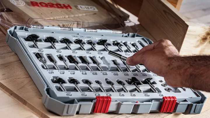 Person selects a drill bit from a plastic case containing an organized set of bits.