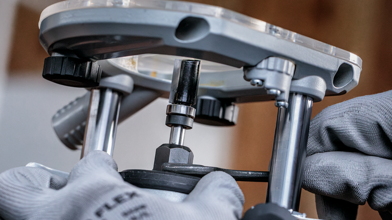 Person wearing safety equipment adjusts a metal router tool.