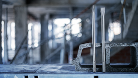 Two metal chisels are standing upright in a concrete block at a construction site.