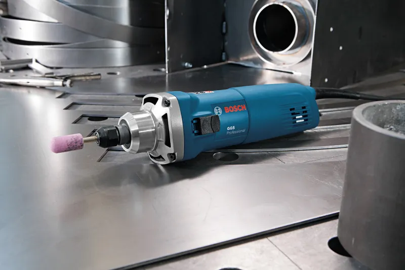 Straight grinder with a mounted abrasive point rests on a metal work surface.